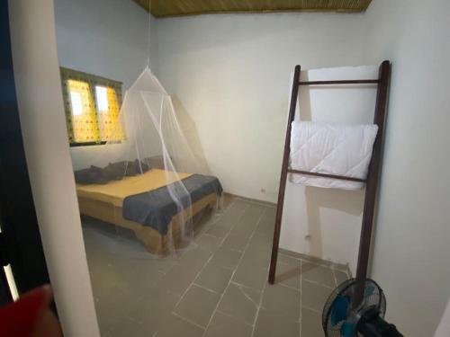 Un dormitorio con una cama y una escalera en una habitación en Petite maison en bord de mer en Palmarin Nguèdj