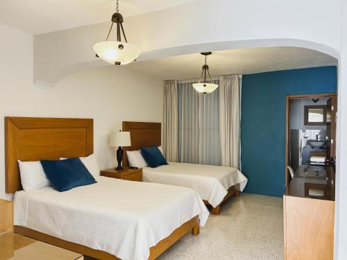 two beds in a hotel room with blue walls at Casa Amarilla in Guanajuato
