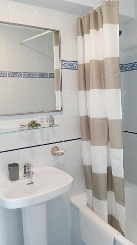a bathroom with a sink and a shower curtain at Pensión liebana in San Vicente de la Barquera