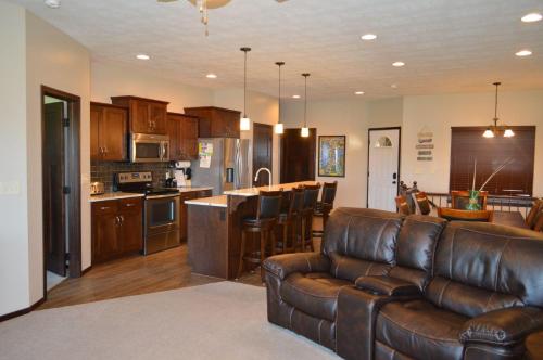 a living room with a leather couch and a kitchen at Bridges Bay Vacation Cabin 185 in Arnolds Park