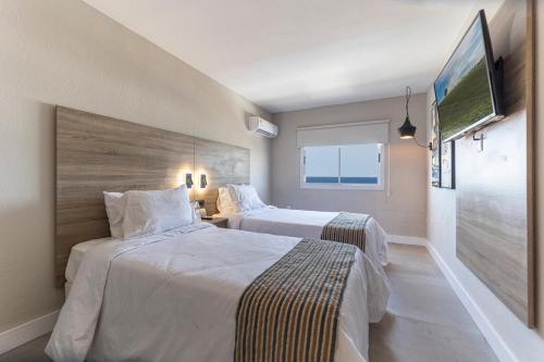 Habitación de hotel con 2 camas y TV de pantalla plana. en Nobile Hotel Montoya en Punta del Este