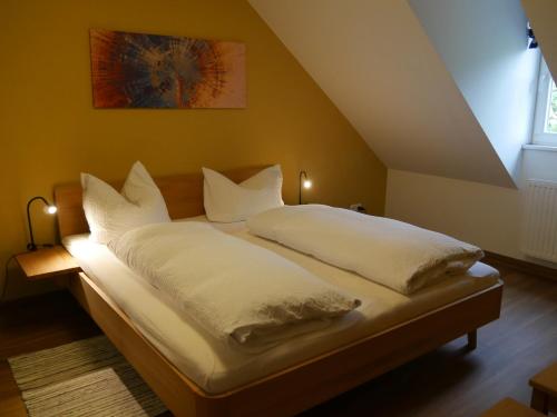 a bed with white sheets and pillows in a room at Lindenhof Wohnung 3, Dachgeschoß in Vipperow