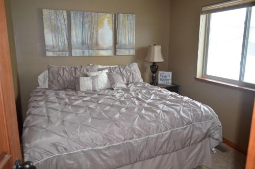 1 dormitorio con 1 cama con edredón gris y ventana en Bridges Bay Vacation Cabin 69, en Arnolds Park