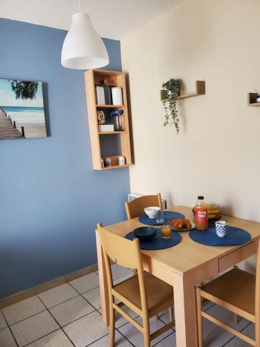 une table à manger avec des chaises et un mur bleu dans l'établissement Résidence les aloès T2 , idéal 2 adultes 2 enfants à 2 minutes de la mer, à Cerbère
