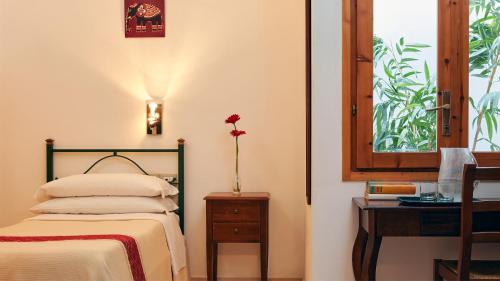une chambre avec un lit, une table et une fenêtre dans l'établissement Cagliari Novecento, à Cagliari