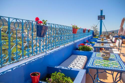a row of tables with plants on a fence at VANCII Hotel in Chefchaouene