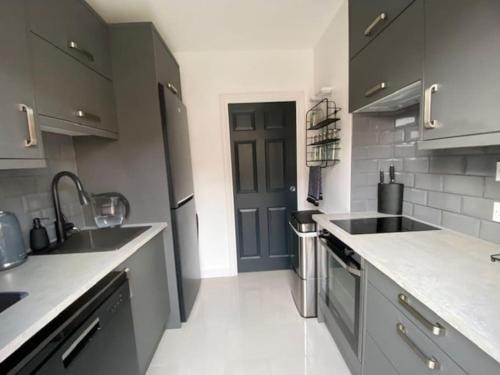 a kitchen with a sink and a dishwasher at Modern 1 bedroom flat with patio garden & parking in Ashford