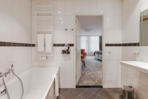 een witte badkamer met een bad en een wastafel bij Boutique Hotel Jeroen in Den Bosch