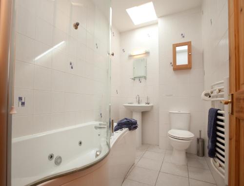 a bathroom with a tub and a toilet and a sink at The Steading, Back Borland Holiday Cottages in Stirling