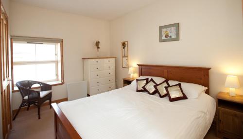 a bedroom with a bed and a chair and a window at The Steading, Back Borland Holiday Cottages in Stirling
