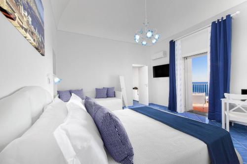 a white bed in a room with a view of the ocean at BlueVista Dreamscape Home -Terrace Jacuzzi/Hot Tub in Positano