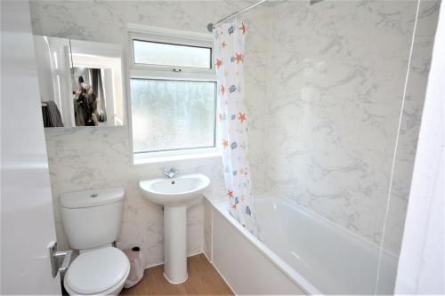 a white bathroom with a toilet and a sink at 4 Bedroom House in East London in London
