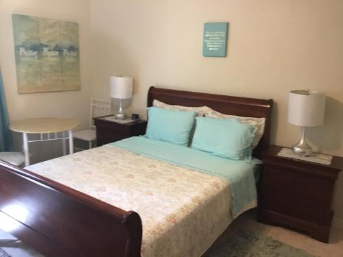 Schlafzimmer mit einem Bett mit blauen Kissen und einem Tisch in der Unterkunft Hills Royale Villa -Ironshore Montego Bay in Montego Bay