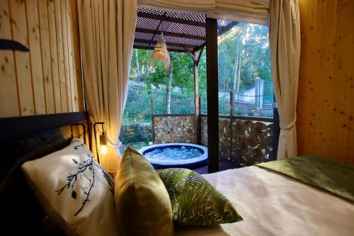 a bedroom with a bed and a window with a tub at Bruval Eco Retreat in Sandim