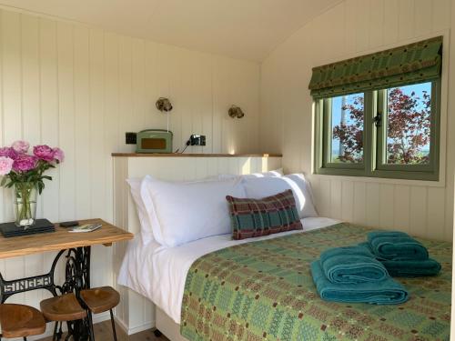 a bedroom with a bed with a table and a window at The Woolly Sheep Shepherd Huts in Whitland