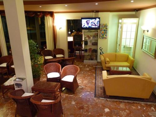una hall con divano, sedie e TV di Hotel Gambrinus a Lido di Jesolo