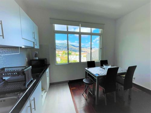 uma cozinha com uma mesa com cadeiras e uma janela em One bedroom house with sea view terrace and wifi at Funchal 4 km away from the beach no Funchal