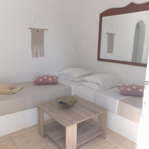 two twin beds in a room with a table at Sagma Central Rooms in Perissa