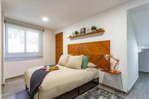 een slaapkamer met een bed met een houten hoofdeinde bij Modern Apartment with Jacuzzi and Pool in Valle de Bravo
