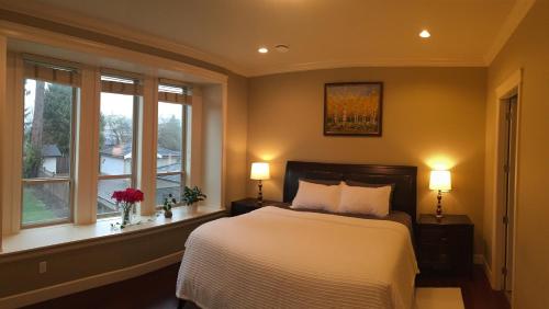 a bedroom with a bed and two windows at Imperial House in Burnaby