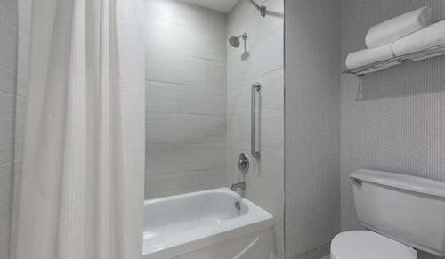 uma casa de banho branca com uma cortina de chuveiro e um WC. em The Simon Hotel Sydney em Sydney