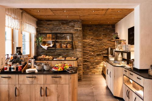 a kitchen with wooden cabinets and a stone wall at Hotel Brunnenhof in Neustift im Stubaital