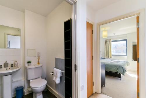 a bathroom with a toilet and a sink and a bed at Luxe 1 bed flat 5 mins to Stratford - Free Parking in London