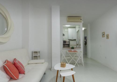 a white living room with a white couch and a table at Lovely studio at the city heart! in Málaga