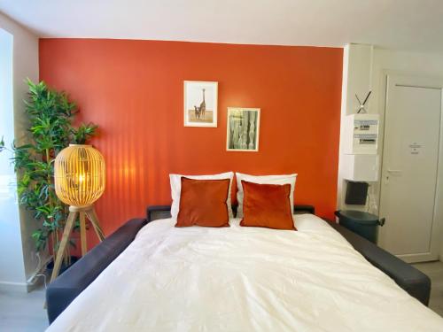 a bedroom with a bed with an orange wall at Le Terracotta - Confort en plein centre in Montaigu-Vendée
