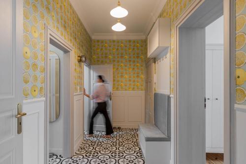 a woman walking into a hallway with yellow wallpaper at Lion Apartments -Juicy Sopot Premium Familly Stay 200 m from the sea in Sopot