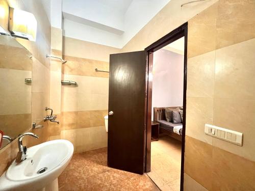 a bathroom with a sink and a door leading to a bedroom at Room with attach washroom on main road- Rajiv Chowk Gurgaon in Gurgaon