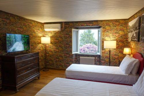 a bedroom with two beds and a tv and a window at CASA VASCONI CERNOBBIO in Cernobbio