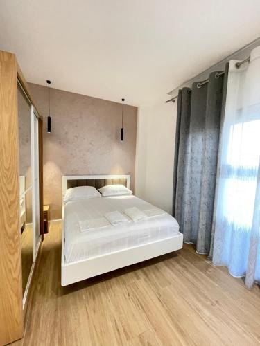 a bedroom with a white bed and a large window at Arial Trinity Suites in Vlorë