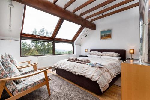 a bedroom with a large bed and two windows at Hafod Rowen in Llangelynin