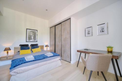 ein Schlafzimmer mit einem Schreibtisch und einem Bett mit blauen und gelben Kissen in der Unterkunft STANDING - NEUF - Croisette- Palais des festivals - 6 pers -3 chbres in Cannes