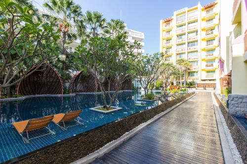 a swimming pool with chairs and trees and a building at Mykonos Condo in Hua Hin