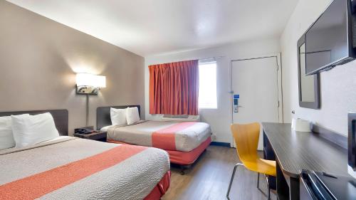 Motel 6-Gallup, NM في غالوب: غرفة فندقية بسريرين ومكتب