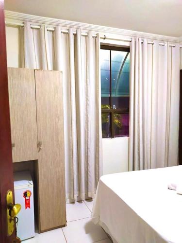 1 dormitorio con 1 cama y una ventana con cortinas en Pousada Nacional Orla, en Maragogi