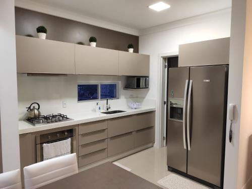 La cuisine est équipée d'un réfrigérateur et de placards en acier inoxydable. dans l'établissement Apartamento luxo Meia Praia, à Itapema