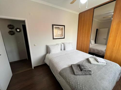 ein Hotelzimmer mit einem Bett und einem Spiegel in der Unterkunft Apartamento Barão in Amora