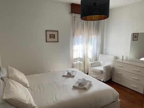 a white bedroom with a bed and a chair at [Pvt Terrace] Connected To Duomo in Sesto San Giovanni