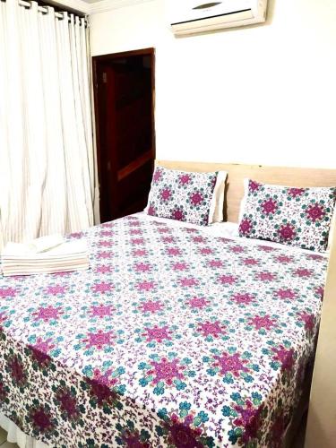 1 cama con edredón de flores y 2 almohadas en Pousada Nacional Orla, en Maragogi