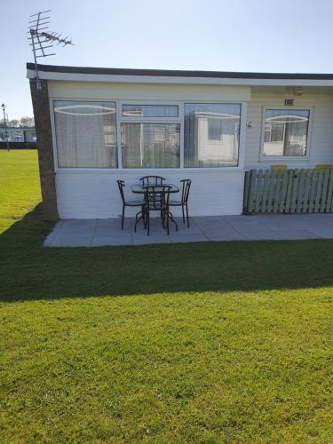 a patio with a table and chairs in front of a house at Sands Holiday Chalet Dog friendly, free wifi, swimming pool and club passes included in Scratby