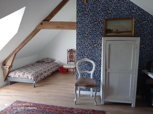1 dormitorio con 1 cama y 1 silla en el ático en Chez Catherine, en Rochefort-en-Terre