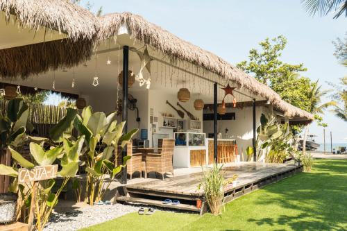 une maison avec un toit de chaume et une terrasse couverte dans l'établissement Sunset Villas Palauig Zambales, à Palauig