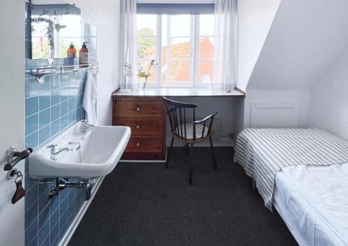 a small bathroom with a sink and a bed at Pension Sandbogaard in Sandvig