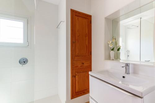 Baño blanco con lavabo y espejo en Villa Can Soler, en Alcudia