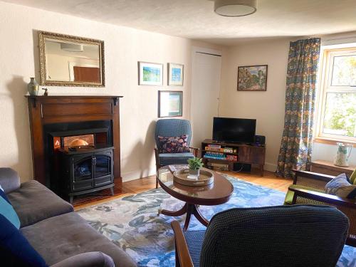 a living room with a couch and a table and a fireplace at Wee Silverburn in Whiting Bay