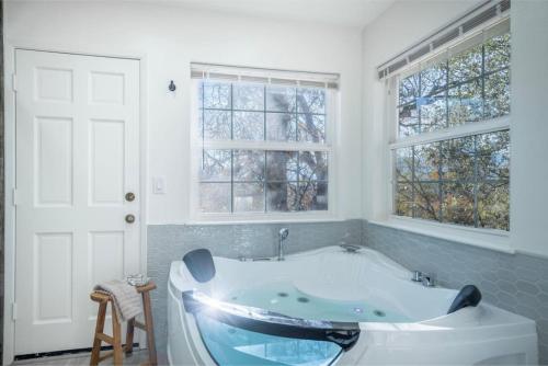 a bath tub in a bathroom with two windows at Wooded Hills Mountain home with Hot tub, Jacuzzi, Game Room, Pool Table in Oakhurst