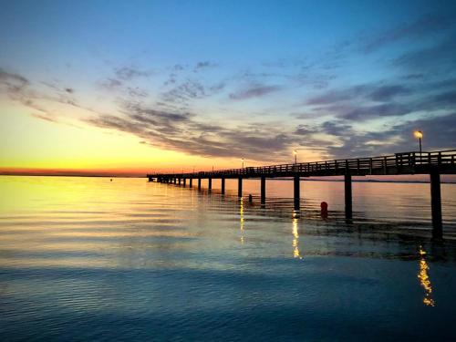 ein Pier auf dem Wasser mit Sonnenuntergang im Hintergrund in der Unterkunft Residence Black Eagle Lubmin Strand in Lubmin